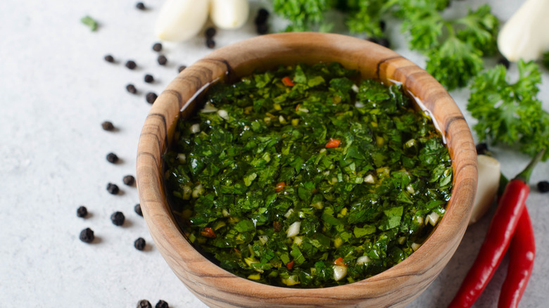 Wooden bowl of homemade fresh chimichurri sauce.