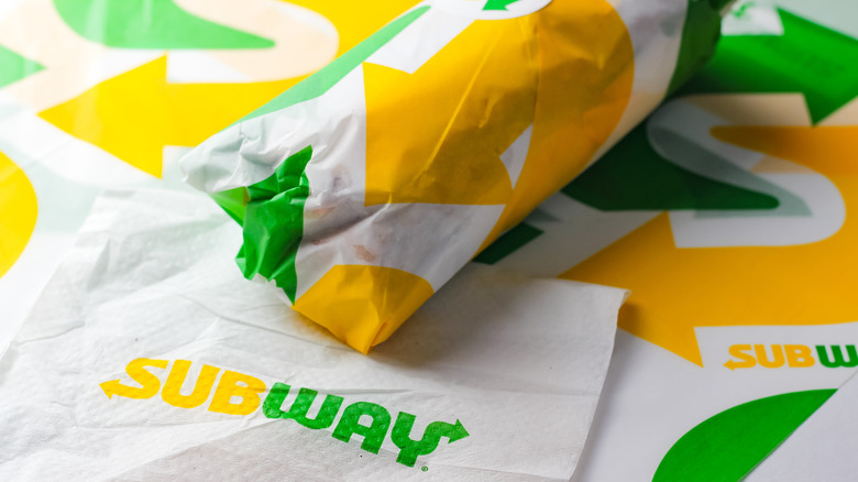Wrapped Subway sandwich on top of Subway paper and napkin