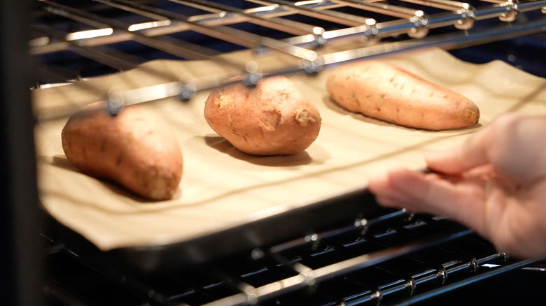 Placing sweet potatoes into the oven. 