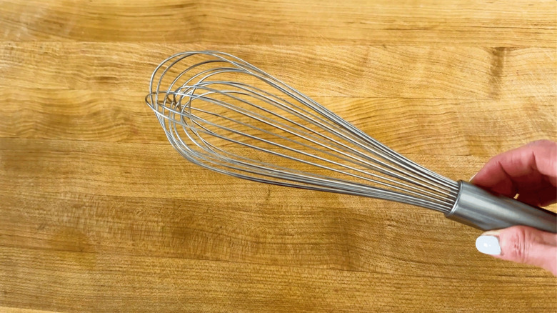 Hand holding a balloon whisk
