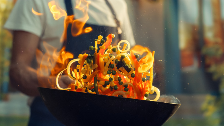 A chef stir frying vegetables.