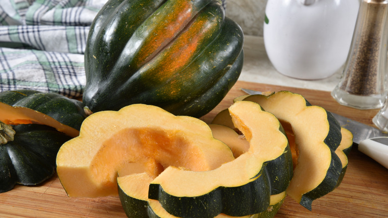 whole acorn squash surrounded by acorn squash slices