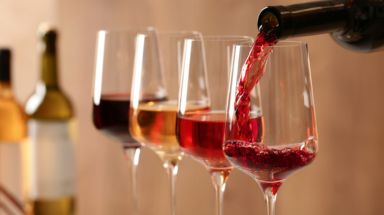 An individual pouring wine into glasses.